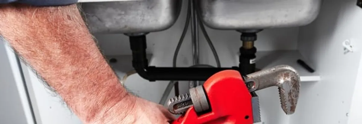 Garbage disposal repair technician tightening drain connections under a kitchen sink in Duluth, MN