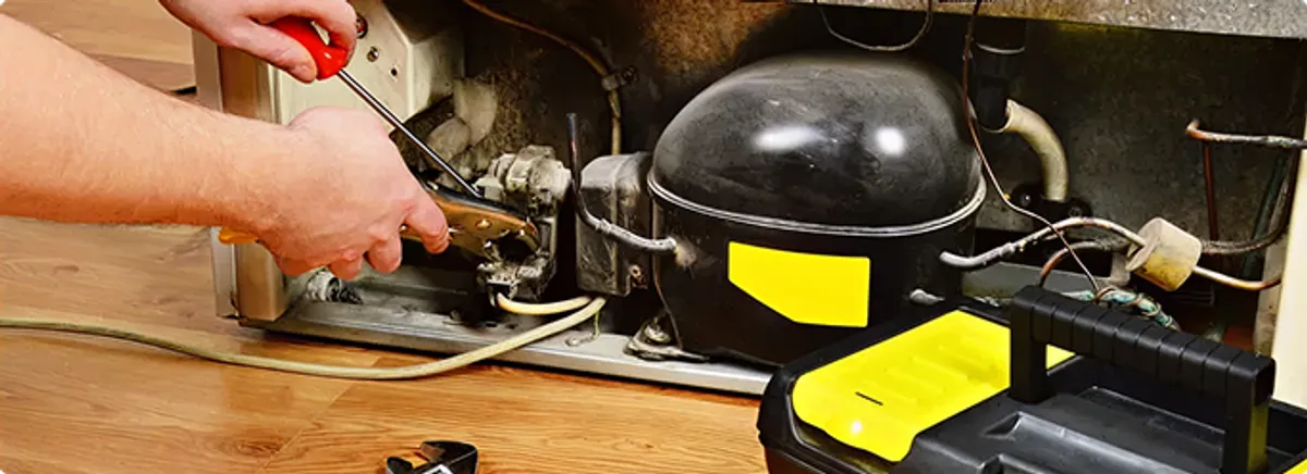 Refrigerator repair technician fixing the compressor and wiring in Carlton, MN