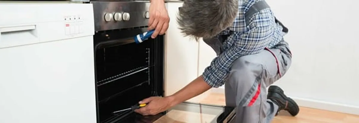 Oven repair technician inspecting and servicing an electric oven in Duluth, MN