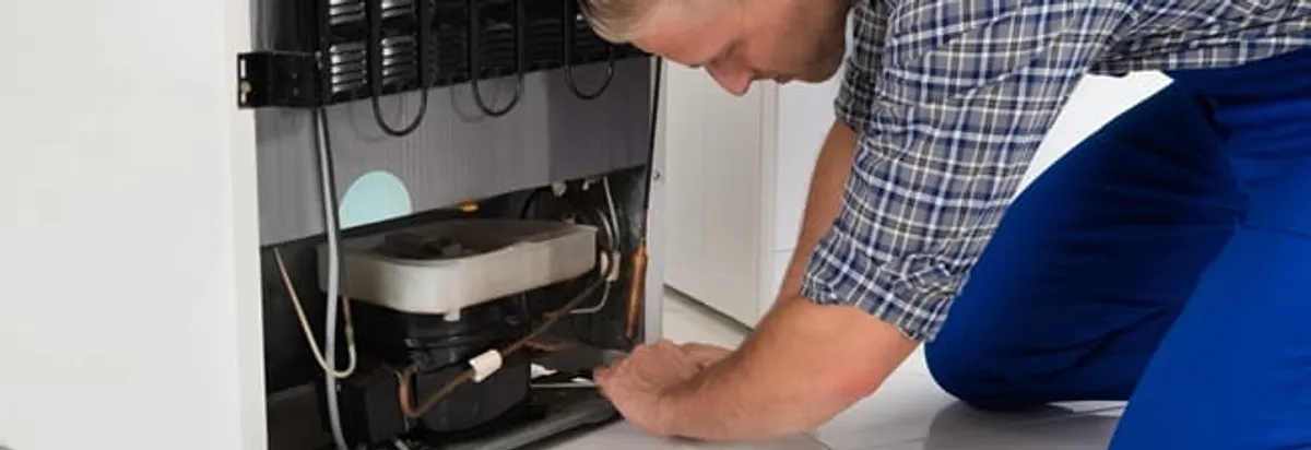 Refrigerator repair technician servicing the compressor and condenser area in Duluth, MN